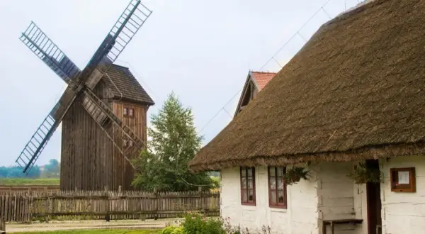 Drewniany wiatrak i biały domek z krytym strzechą dachem tworzą malowniczą zagrodę młynarską w Uniejowie.