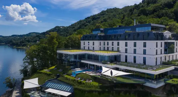 Nowoczesny hotel nad jeziorem Rożnowskim, z basenem i tarasami, otoczony zielenią.