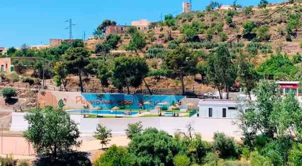 Piscina municipal en el oeste de Almería, rodeada de vegetación y colinas. Un oasis refrescante bajo el sol andaluz.