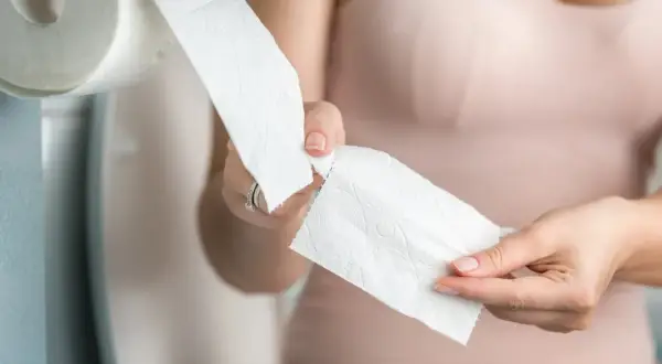 Kobieta zrywa papier toaletowy, zastanawiając się, czy piwo jest moczopędne.