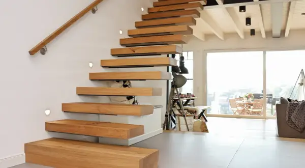 Ein modernes Treppenhaus gestalten: Schwebende Holzstufen mit integrierten Leuchten und einem schlichten Holzhandlauf.