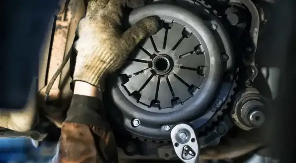 Mechanik w rękawicy próbuje zamontować tarczę sprzęgła. Ciezko wchodzi 1, ale z kluczem nasadowym praca pójdzie sprawniej.