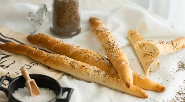 Goldbraune Salzstangen mit Kümmel und grobem Salz, bereit zum Genießen. So einfach kannst du Salzstangen selber machen!