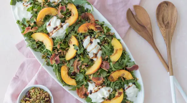Salade d'été avec pêche, burrata crémeuse, roquette, prosciutto croustillant et vinaigre balsamique. Un délice !