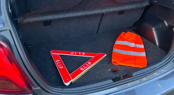 Triangle de signalisation et gilet de haute visibilité dans un coffre de voiture, prêts pour la signalisation dépassement chargement arrière.