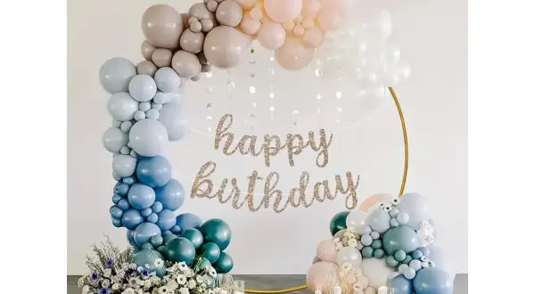 Elegancki łuk do balonów w pastelowych kolorach, ozdobiony girlandą "happy birthday" i kwiatami. Idealna dekoracja na przyjęcie.
