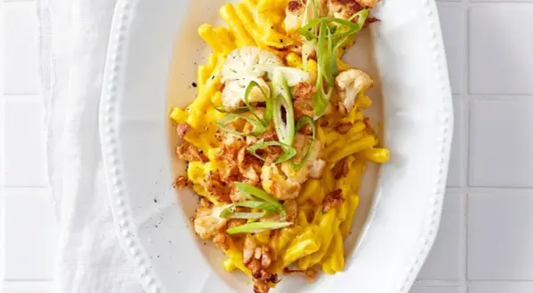 Cremiges Blumenkohl Mac and Cheese mit knusprigen Zwiebeln und Frühlingszwiebeln garniert.
