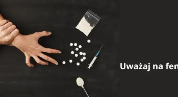Dwie ręce walczą o kontrolę nad przedmiotami związanymi z narkotykami, w tym proszkiem, tabletkami i strzykawką. Uważaj na fentanyl.