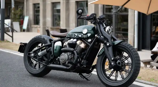 Zielony, stylowy chopper Benda, najmocniejszy chopper 125, z brązowym siedzeniem i czarnymi felgami, zaparkowany na ulicy.