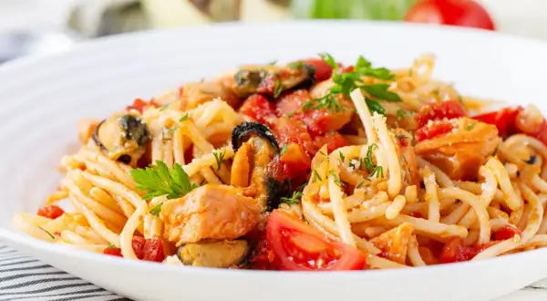 Pyszne spaghetti z owocami morza, pomidorami i świeżą natką pietruszki.