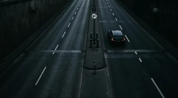 Czarny samochód jedzie pustą drogą. Zastanawiasz się, ile schnie asfalt po deszczu, gdy tak pięknie odbija światła.