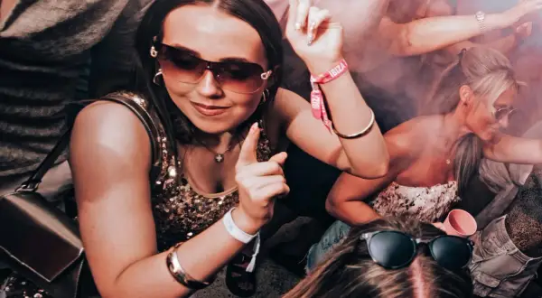 Ragazze danzano in un locale, con braccialetti "Ibiza" visibili. Un'atmosfera da festa che fa pensare al calendario eventi Ibiza.