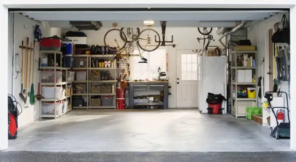 Organizzazione garage con scaffalature, biciclette appese e attrezzi. Ottime idee garage fai da te per uno spazio funzionale.