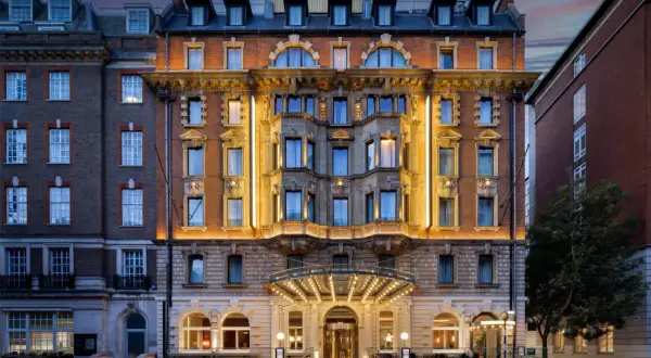 Elegancki hotel w Londynie z oświetloną fasadą i wejściem, nocą.