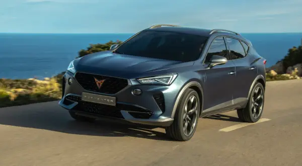 Niebieski SUV Cupra Formentor jedzie nad morzem. To jeden z wielu modeli, które można znaleźć, przeglądając marki samochodów alfabetycznie.