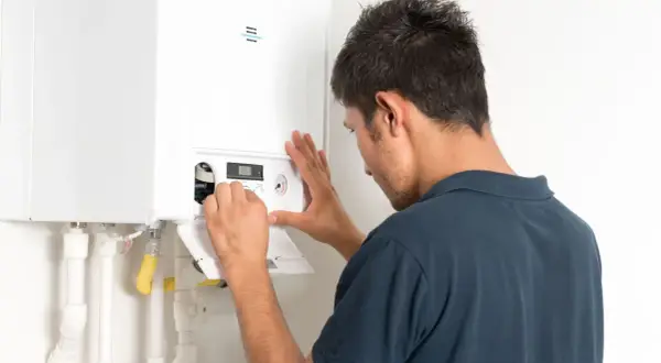 Tecnico controlla la caldaia che non carica acqua, regolando i comandi sul pannello.