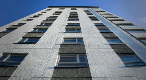 Facciata di un palazzo con file di finestre, sotto un cielo blu. Potrebbe rappresentare il punteggio minimo per casa popolare.