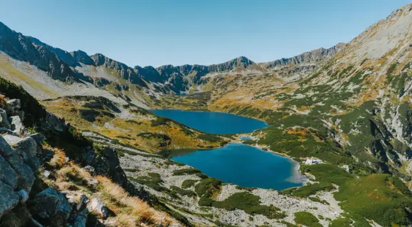 Widok na szlak z Doliny Pięciu Stawów do Morskiego Oka. Błękitne jeziora otoczone skalistymi zboczami i zieloną roślinnością.