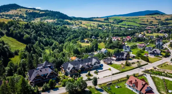 Gorce: malownicza wieś z pensjonatami i domami w górskim krajobrazie. Idealne miejsce, by znaleźć nocleg i odpocząć.