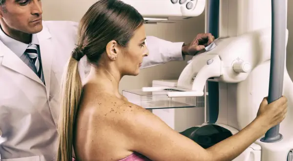 Lekarz nadzoruje badanie mammograficzne, które może być wstępem do biopsji gruboigłowej. Kobieta przygotowuje się do procedury.