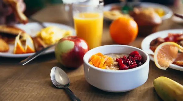 Colazione pre workout: porridge con frutta secca, succo d'arancia, mela e banana. Energia per iniziare la giornata!