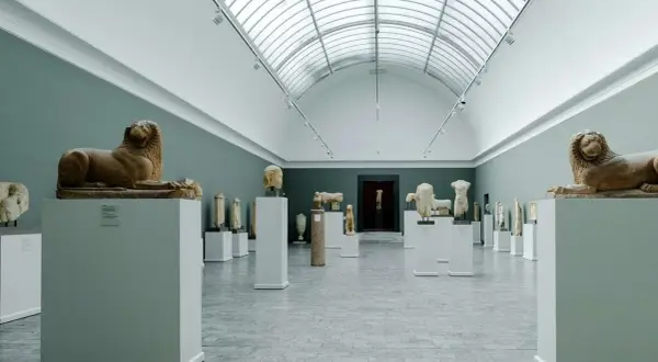 Ancient sculptures, including lion statues, are displayed in a grand hall, showcasing the impressive collection of Copenhagen art galleries.