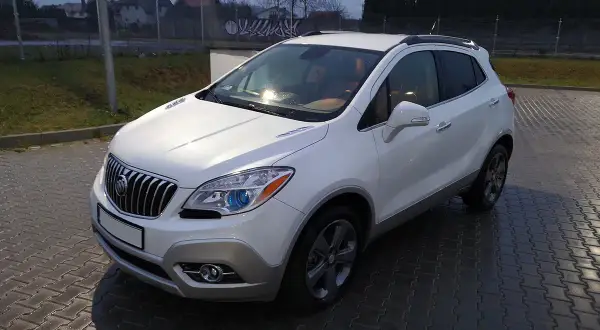 Biały Buick Encore stoi na mokrej, brukowanej nawierzchni.