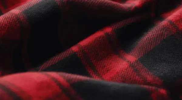 Rotes und schwarzes Karomuster auf weichem Stoff. Das ist typisch für Flanell, das sich warm und gemütlich anfühlt.