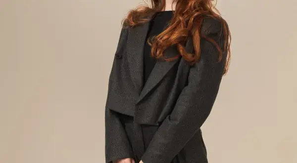 Elegancki komplet spodnie z tuniką w ciemnoszarym kolorze. Modelka ma rude włosy.