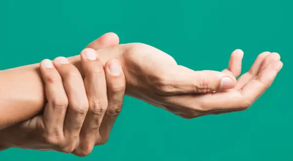 Mano che si tiene il polso, indicando dolore o fastidio, forse legato all'artrite polso.
