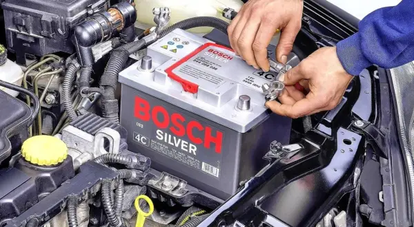 Dobór akumulatora do pojemności silnika: mechanik podłącza akumulator Bosch Silver 44Ah do samochodu.