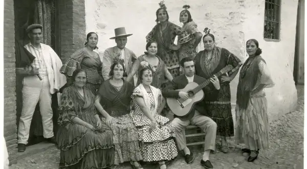 Grupo de gitanos en Granada, con un hombre tocando la guitarra. Captura la esencia del significado del flamenco.
