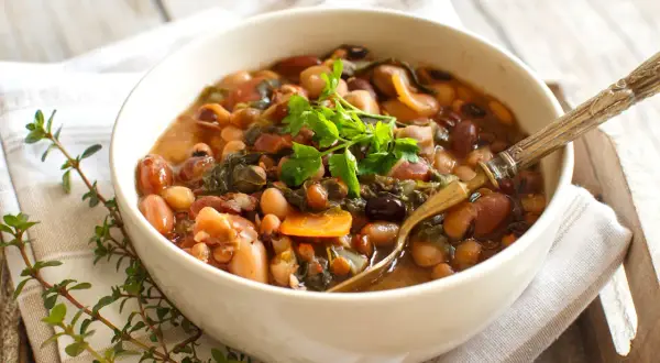 Una ciotola di fagioli misti, verdure e carote, guarnita con prezzemolo fresco. Perfetta per la cottura fagioli secchi.
