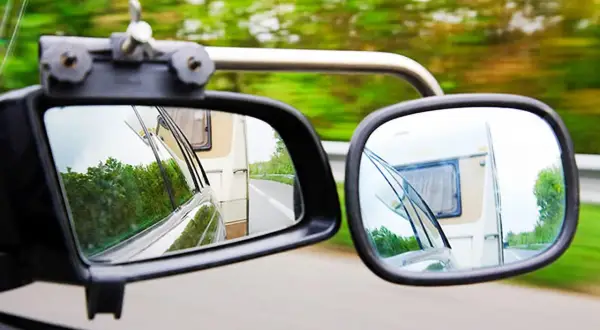 Zwei Spiegel zeigen die Straße und einen Wohnwagen. Für sicheres Fahren mit Anhänger ist der Wohnwagenspiegel Pflicht.
