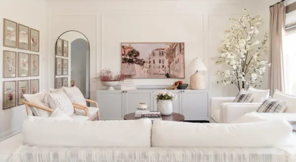 Elegant living room with a Venetian canal painting above a gray credenza. The walls feature decorative molding, adding a classic touch.