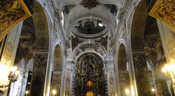 Interior de la iglesia de la Magdalena, con bóvedas ornamentadas, arcos y un retablo dorado.