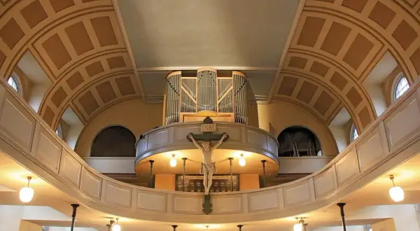 Orgel und Kruzifix im St. Pauli Dom. Die geschwungene Empore und die kunstvolle Deckenkonstruktion schaffen eine feierliche Atmosphäre.