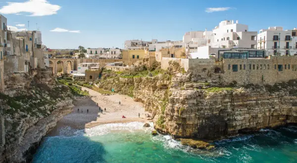 Un'idea per il tuo itinerario Puglia 7 giorni in macchina: la costa rocciosa di Polignano a Mare con la sua spiaggia e le case bianche a picco sul mare.