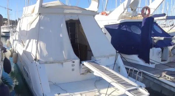 Il Raffaelli Typhoon, un lussuoso yacht bianco, è ormeggiato in un porto. La passerella è estesa, pronta per l'imbarco.