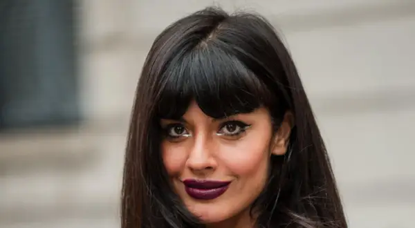 Frau mit dunklem Haar und Pony, der gerade rauswächst, und auffälligem Make-up.