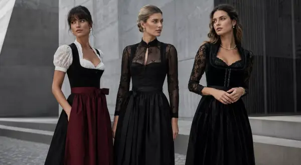 Drei Frauen in eleganten Dirndln. Das schwarze Dirndl mit Spitzenärmeln und dezentem Muster steht für moderne Eleganz.