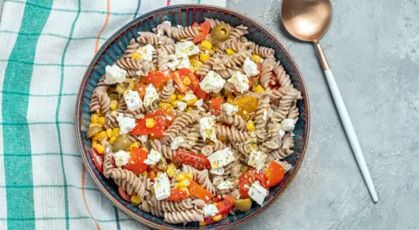 Insalata di pasta integrale con pomodorini, mais, olive e feta. Un condimento pasta per dieta leggero e gustoso.