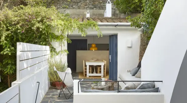 Un moderno patio andaluz con muebles blancos, vegetación exuberante y un rincón acogedor para relajarse.