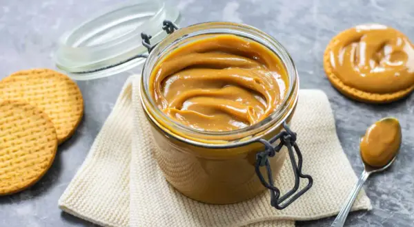 Un vasetto pieno di cremoso dulce de leche, pronto per essere spalmato su biscotti croccanti.
