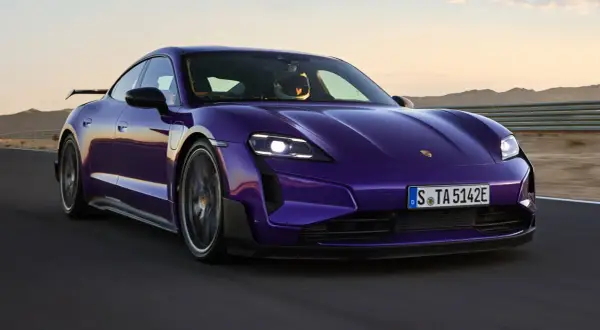 Fioletowy Porsche Taycan na torze wyścigowym. Kierowca w kasku. Sprawdź, jaka jest porsche taycan cena.