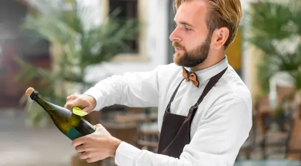 Barman przygotowuje szampana, dbając o to, by nie psuł się, zanim trafi do klienta.