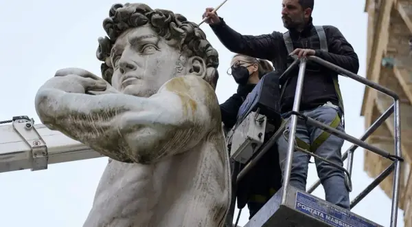 Restauratoren arbeiten auf einer Hebebühne am David von Michelangelo. Wo steht der David von Michelangelo? In Florenz, Italien.