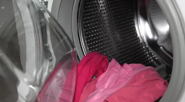 Otwarta pralka Beko z różowymi ubraniami w środku. Zastanawiasz się, jak odblokować pralkę Beko?