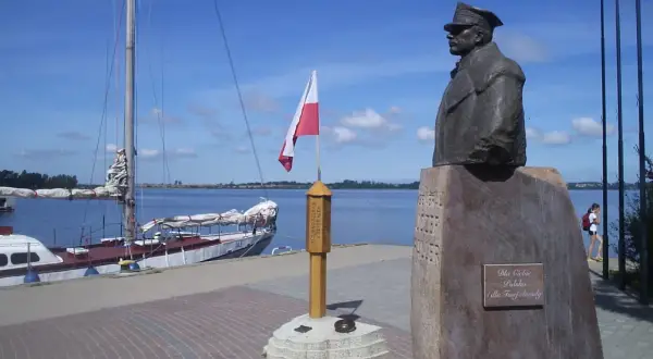 Pomnik upamiętniający zaślubiny Polski z morzem. Obok żaglowiec i polska flaga.