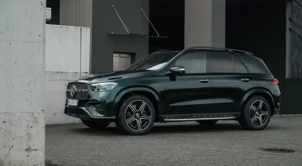 Ciemnozielony Mercedes GLE 350 stoi przed nowoczesnym budynkiem.